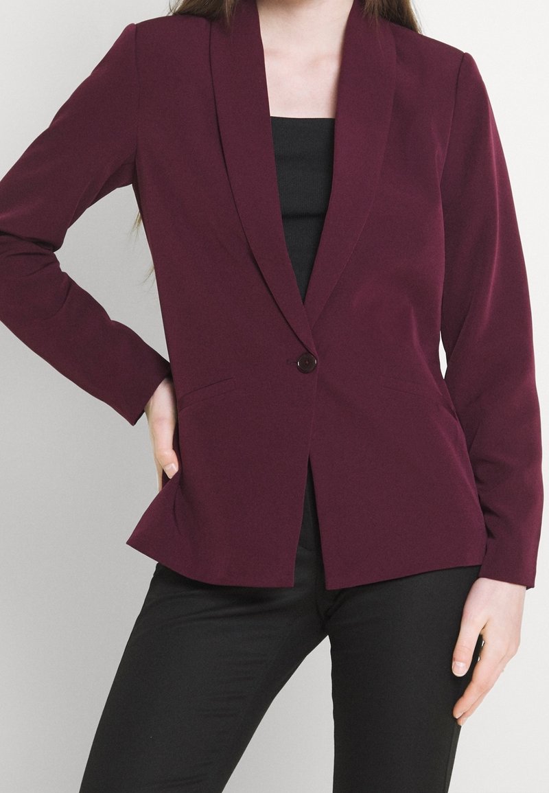 Bordeaux blazer met een geknipt revers, enkele knoopsluiting en zijzakken. Gemaakt van gladde stof, met een getailleerde pasvorm.