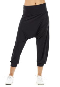 Pantalons de style harem noirs avec une large ceinture élastique et des poignets froncés, dotés d'un tissu ample et fluide pour le confort et la liberté de mouvement.