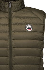 Olive green quilted sleeveless vest with front zipper and round patch logo showing scooter silhouette and text "Just Over The Top JOTT".