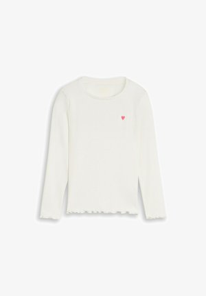 Wit shirt met lange mouwen, ronde hals en een klein roze hart op de linkerborst, met golvende zomen aan mouwen en onderkant.