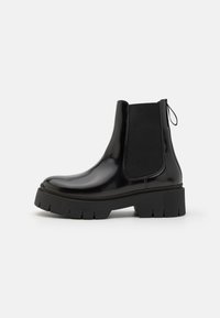 Ghete Chelsea din piele lacuită neagră, cu talpă din cauciuc chunky, panouri elastice pe laturi și un tab pentru a le îmbrăca cu ușurință.