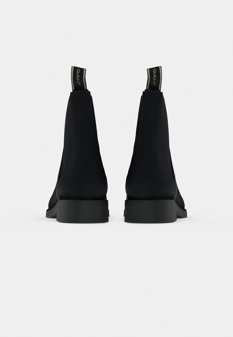 Paire de bottines noires avec languettes de traction à logo, vues de dos sur un fond uni gris clair.