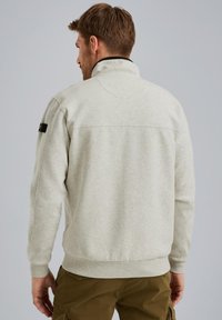 Pull en polaire gris clair avec col montant et poignets côtelés, présentant une accento noir sur l'épaule. Conception simple, sans motifs visibles.