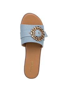 Sandal in denim blu con una larga fascia e un centrale embellimento circolare in tono oro con borchie, dotato di una suola liscia marrone.