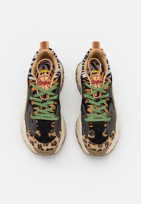 Paire de baskets épaisses avec imprimés léopard, tigre et zèbre, lacets verts, semelles beiges, et étiquette de la marque Buffalo sur la languette et la boucle du talon.