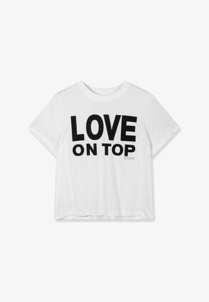 T-shirt blanc à manches courtes avec un texte noir audacieux "LOVE ON TOP" et un petit "10DAYS" imprimés au centre devant.