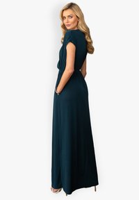 Tummansininen maksimekko lyhyillä hihoilla, vyötäröltä kireä, sivutaskut ja sileä pinta. Laskeutuu elegantisti lattiaan.