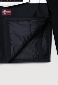 Zwart jasje met een gewatteerde voering, voorzien van een ritszak en een geborduurde Noorse vlagpatch aan de buitenkant.