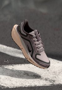 Adidași de alergare violet deschis cu un superior din plasă, accente negre și o talpă bej. Prezintă sistem de închidere cu șireturi și un design durabil cu detaliu logo.