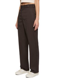 Bruna skräddarsydda byxor i slitstark tyg, med rak ben-design, bred midja och sidofickor, kombinerat med vita sneakers.