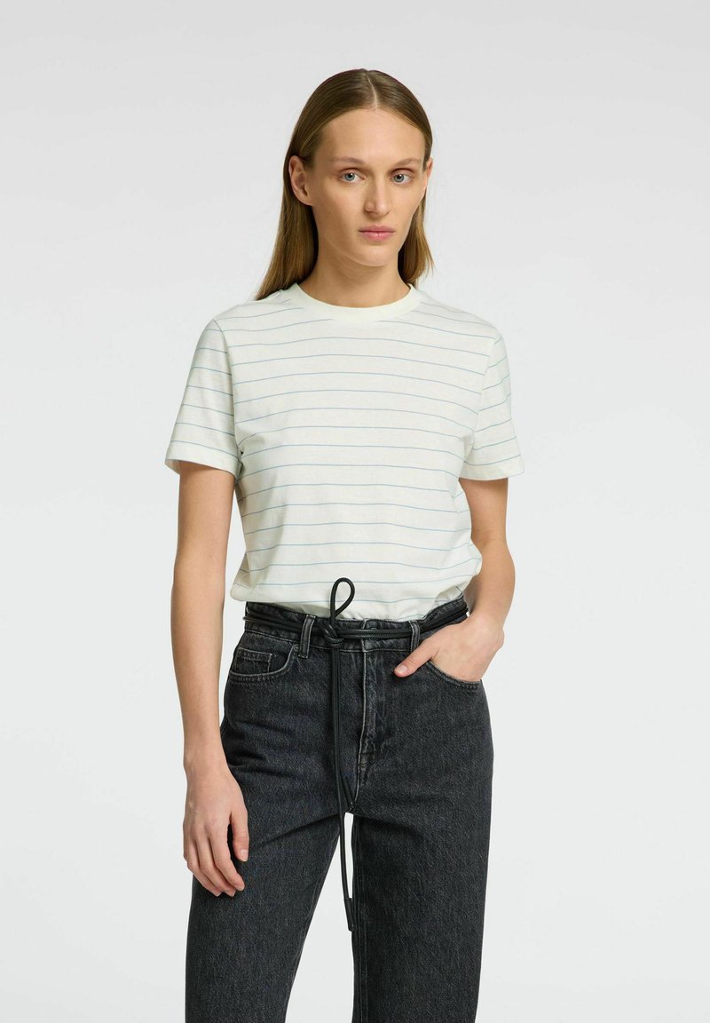Bomullströja med rund hals, ljusbeige med marinblå horisontella ränder. Kombinerad med högmidjade svarta denimjeans med snörning.