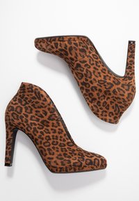 Bottes à talons hauts en imprimé léopard avec une texture en daim brun doux, bout pointu et talon aiguille noir. Aucun matériel visible.