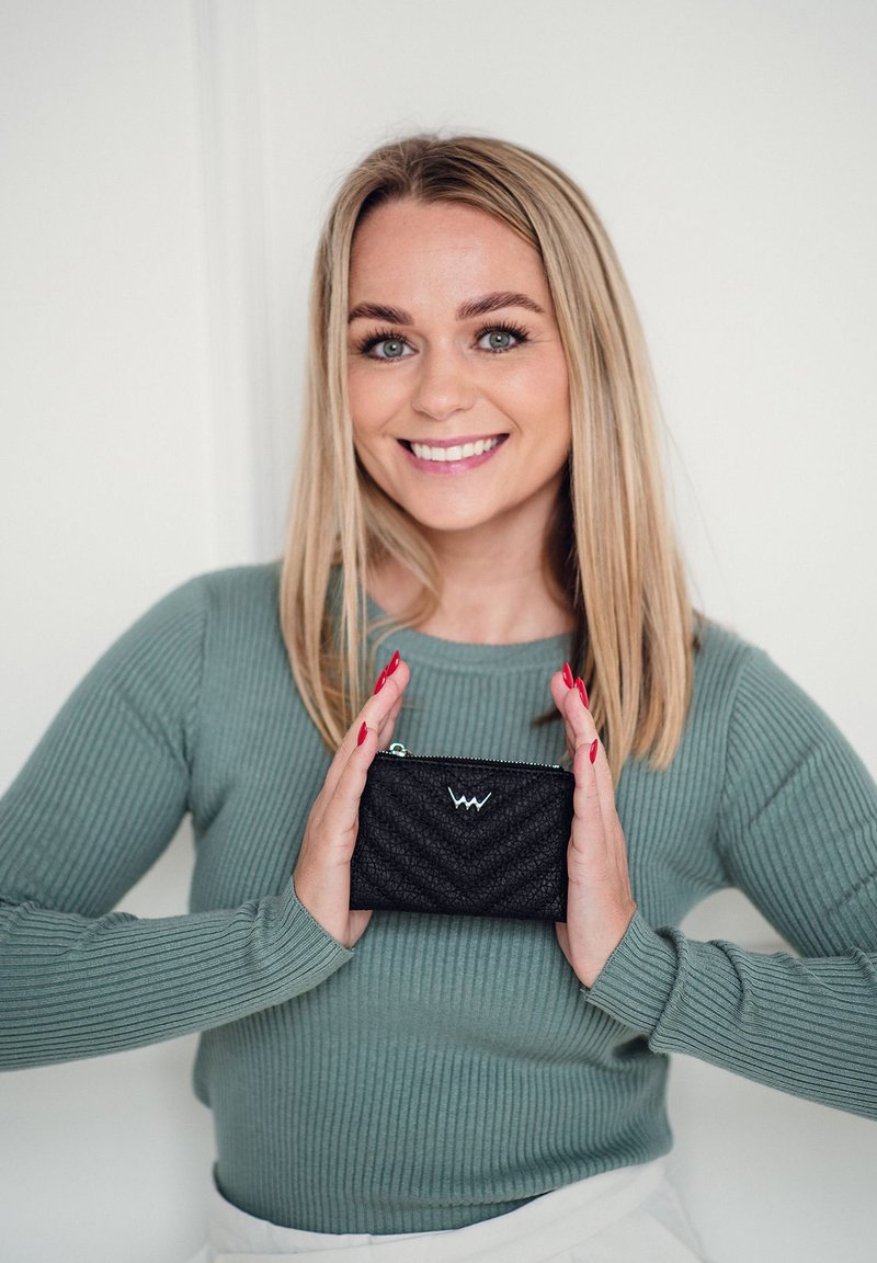 Black textured wallet with a zigzag pattern and a light blue zipper, held in hands against a neutral background.