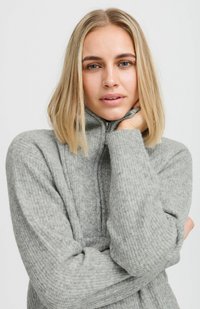 Sudadera de forro polar gris con cremallera y textura acanalada. Presenta un cuello alto y un ajuste cómodo, ideal para un estilo casual.