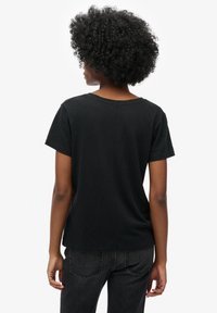 Zwarte t-shirt met korte mouwen, gemaakt van een zachte stof, met een ronde hals en een ontspannen pasvorm, gezien vanaf de achterkant.