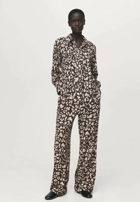 Dvodelni komplet pižame v črni barvi z bež abstraktnim vzorcem; vključuje srajco z ovratnikom in gumbi ter široke hlače. Gladek tekstura tkanine.