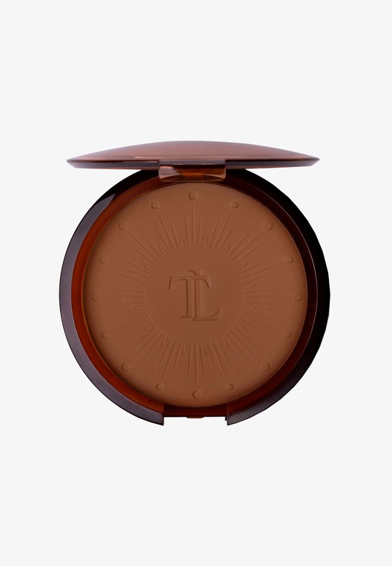 Runde Bronzer-Compact mit einem glänzenden braunen Äußeren. Die Oberfläche zeigt ein Sonnenstrahlenmuster und ein geprägtes Logo, mit einem glatten, sandfarbenen Puder im Inneren.