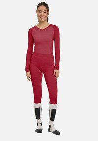 Rotes Langarm-Baselayer und passende Leggings aus dehnbarem Stoff mit einem strukturierten Muster an der Oberseite. Knielange Socken in Creme und Grau.