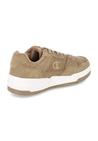 Sandaal van tan suède met een afgeronde neus, witte buitenzool, bijpassende veters en een subtiel logo aan de zijkant. Voorzien van een gevoerde kraag voor comfort.