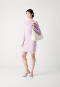 Long-sleeve, form-fitting mini dress in soft lilac with a subtle textured pattern, paired with a cream-colored hobo bag and strappy heels.