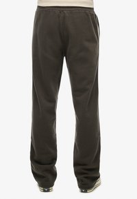 Donkergrijze joggingbroek met een elastische tailleband, zijzakken en taps toelopende pijpen. Zachte stof met een gladde textuur en minimale ontwerpelementen.