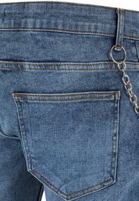 Jeans en denim bleu clair avec une silhouette classique, présentant des coutures orange et une chaîne fixée à une attache de ceinture. Poche arrière visible.