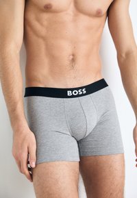 Gray cotton boxer briefs with a black elastic waistband featuring "BOSS" in white lettering, showcasing a snug fit and smooth texture.