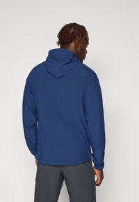 Blauwe hoodie met lange mouwen, gemaakt van lichtgewicht stof. Heeft een gestructureerd oppervlak en een verstelbare kap voor een veilige pasvorm.