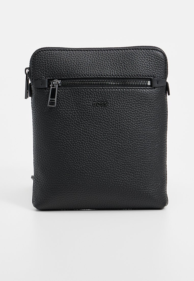 Sac bandoulière en cuir noir avec une finition texturée, présentant une poche zippée à l'avant et un logo discret. Forme rectangulaire aux bords lisses.