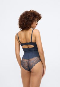 Tengerészhadtestú bodysuit sima, rugalmas anyagból. Csipke részletekkel a háton és a derékon, valamint egy kulcslyuk kivágású dizájnnal rendelkezik.