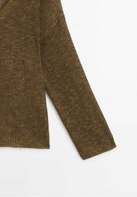 Manche de pull en tricot brun à manches longues avec un motif texturé et un tricot lâche sur fond blanc.