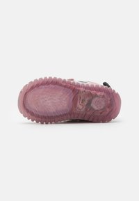 Transluzenter pinker Gummi-Außensohle mit strukturiertem Grip-Muster. Verfügt über ein schwarzes Obermaterial mit bunten Akzenten und eine sichtbare Dämpfungseinheit.