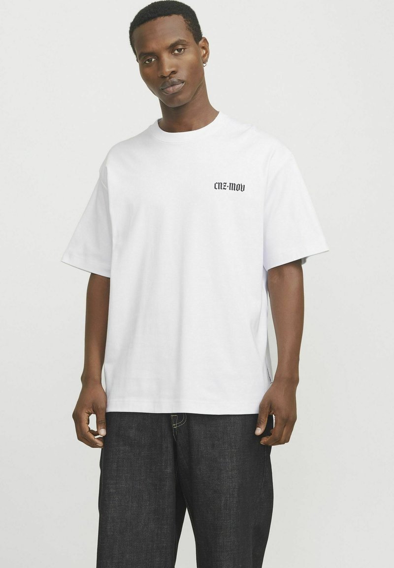 Hvid bomulds t-shirt med korte ærmer og rund hals, prydet med sort tekst "CNZ-MOV" nær venstre bryst, afslappet pasform.