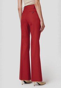 Rozszerzane czerwone spodnie wykonane z teksturowanej tkaniny, z wysokim stanem, dwiema tylnymi kieszeniami z guzikami oraz dopasowanym krojem.
