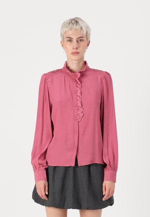 Pink long-sleeve blouse with ruffled collar, button front, and decorative shoulder accents. Soft fabric with a smooth texture.