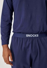 Marineblauw top met lange mouwen en bijpassende joggingbroek, met een zachte textuur en een elastische tailleband met "SNOCKS"-branding in het wit.