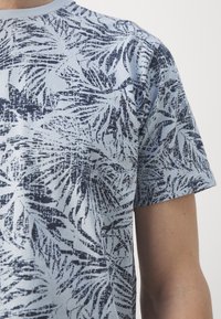 Short-sleeve shirt in light blue cotton with a dark blue palm leaf pattern. Crew neckline and relaxed fit.