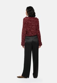 Burgundy cropped sweater with textured knit, paired with black wide-leg trousers and leopard print flats, viewed from the back.