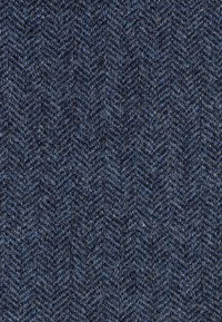 Herringbone raksta audums tumši zilās un gaišāk zilās krāsās, ar teksturētu, austu izskatu un brīviem šķiedru pavedieniem visā virsmā.