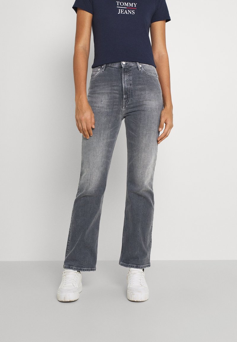 Gray denim jeans with a straight leg cut, featuring subtle fading and a mid-rise waist, paired with a navy T-shirt and white sneakers.