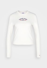 Bílá dlouhá rukávová tričko vyrobené z bavlny, s vyšitém textem "TOMMY JEANS N.Y.C" a květinovými akcenty přes hruď.