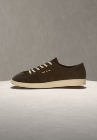 Кафяв велурен нисък кец с бели връзки и подметка, с лого "Paul Smith" отстрани, показан на равна светла повърхност.