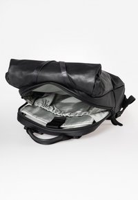 Zaino in pelle nera con chiusura superiore arrotolata, scomparto principale con zip, rivestimento interno argento e tasca elastica interna per l'organizzazione.