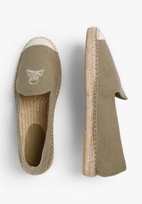 Khaki espadriller med canvas-overdel, beige stof tåhætte og dekorativt kranie- og korsknoglesymbol. Rebvævet sål giver tekstur.