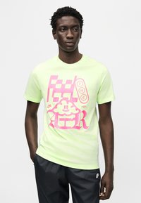 Μπλουζάκι από βαμβάκι σε νέον πράσινο χρώμα με μεγάλο ροζ γραφικό σχέδιο που περιλαμβάνει κείμενο και μοτίβο σύννεφου. Κοντά μανίκια, στρογγυλή λαιμόκοψη, άνετη εφαρμογή.