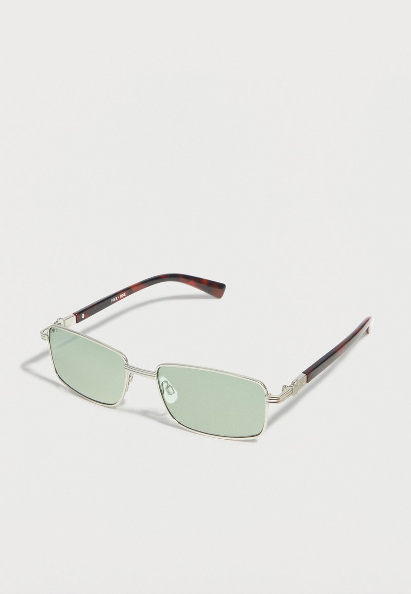Ορθογώνια γυαλιά ηλίου με ασημένιο μεταλλικό σκελετό, φακούς ανοιχτού πράσινου χρώματος και σκουρόχρωμα μπράτσα με μοτίβο χελώνας.