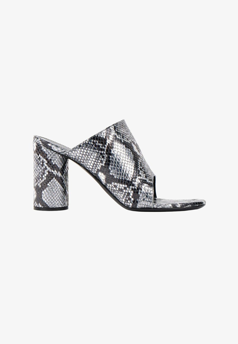 Sandale mule femme à bout ouvert avec motif peau de serpent noir et blanc et talon bloc sur fond blanc.