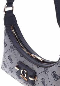 Borsa in tessuto navy con forma curvata, dotata di una cerniera dorata e logo. Accentuata da una superficie decorata e un manico in pelle liscia.