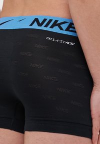 Svarte Nike Dri-FIT boxershorts med en blå livlinje, med et teksturert mønster og logo detaljer. Glatt stoff med en tettsittende passform.