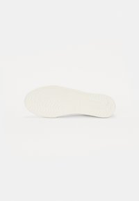 Hvite sneakersåler med teksturert bølgemønster. Laget av gummi, har en glatt kant og rund tådesign.